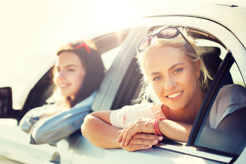 Sommerurlaub, Ferien, Reisen, Roadtrip und Menschen-Konzept – glückliche Teenager-Mädchen oder junge Frauen im Auto am Meer.