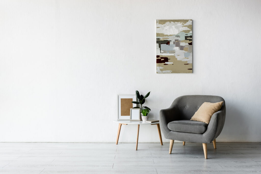 Bequemer Sessel neben einem Couchtisch mit grünen Pflanzen und Bilderrahmen in einem modernen Wohnzimmer.