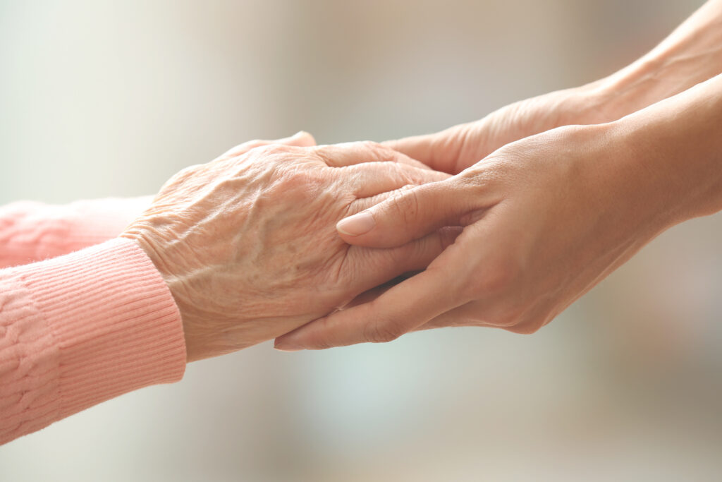 Eine junge Frau hält die Hände einer älteren Frau, Detailaufnahme