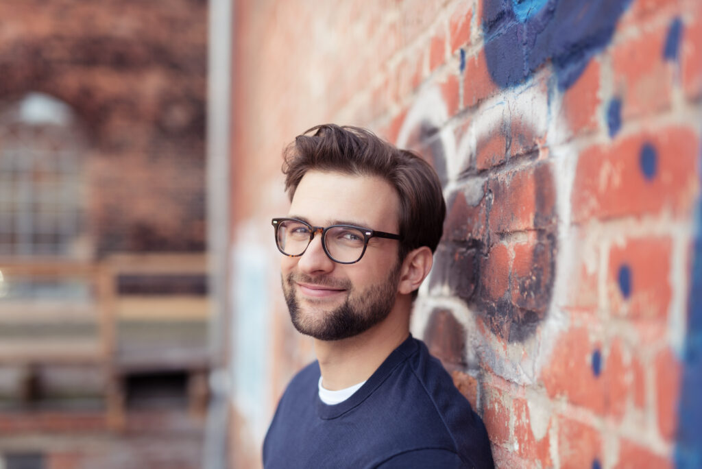 Mann lehnt an einer Backsteinwand